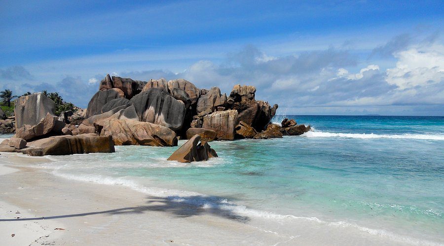 Mocne fale i szeroki piasek na dzikiej plaży Grand Anse, La Digue